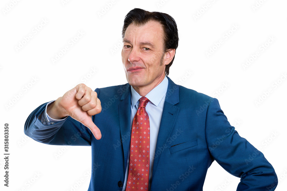 Studio shot of stressed mature businessman giving thumbs down Studio shot of stressed mature businessman giving thumbs down