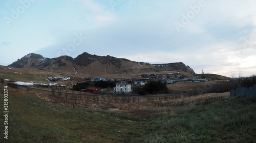 Vik town panoramic view, Iceland, houses sit under mountain range, and church at the top of a hill