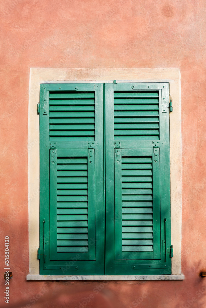 Window closed with wooden shutters on the vintage wall