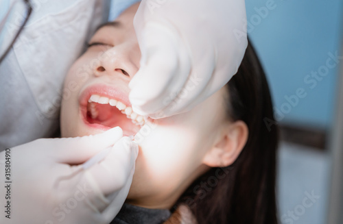 Dentist extracting teeth for young Asian woman