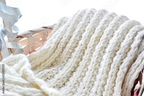 folded long soft warm winter woolen knitted white scarf in basket close up on white background