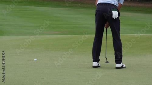 Professional golfer putting golf ball to hole on green golf course on hills in open tournament competition. 