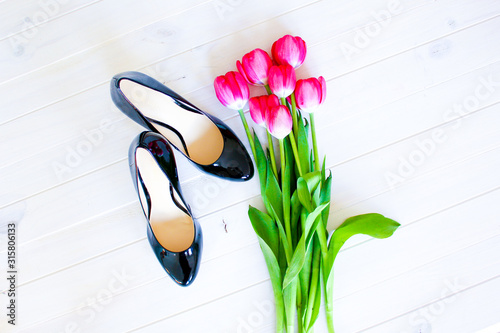Pink tulips & black high heel shoes on white background