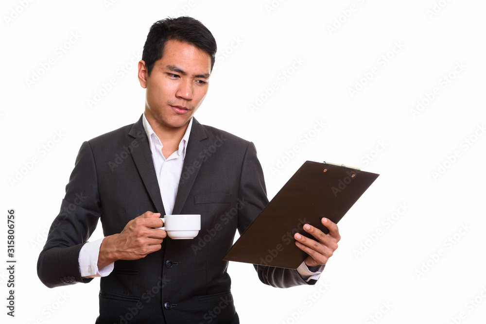 Studio shot of young Asian businessman reading on clipboard whil Studio shot of young Asian businessman reading on clipboard whil