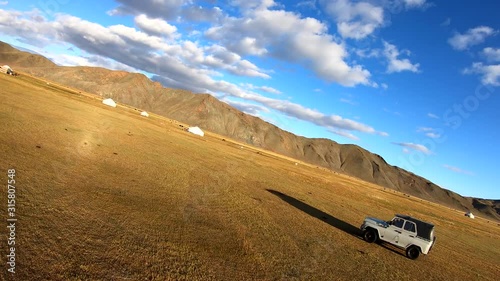 Slow motion FPV, drone shot, around a 4x4 offroad truck, driving across the Gobi desert, in the Altay mountains, sunny day, in Mongolia photo