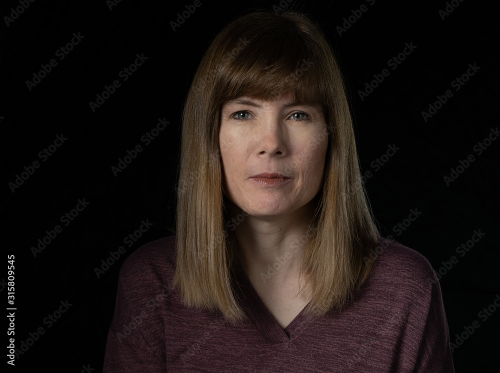 Middle aged woman with serious expression, isolated on dark background Middle aged woman with serious expression, isolated on dark background