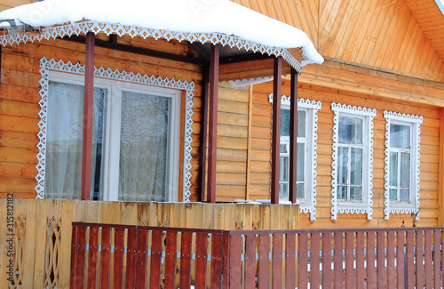 Wooden rural house with openwork frames on the Windows