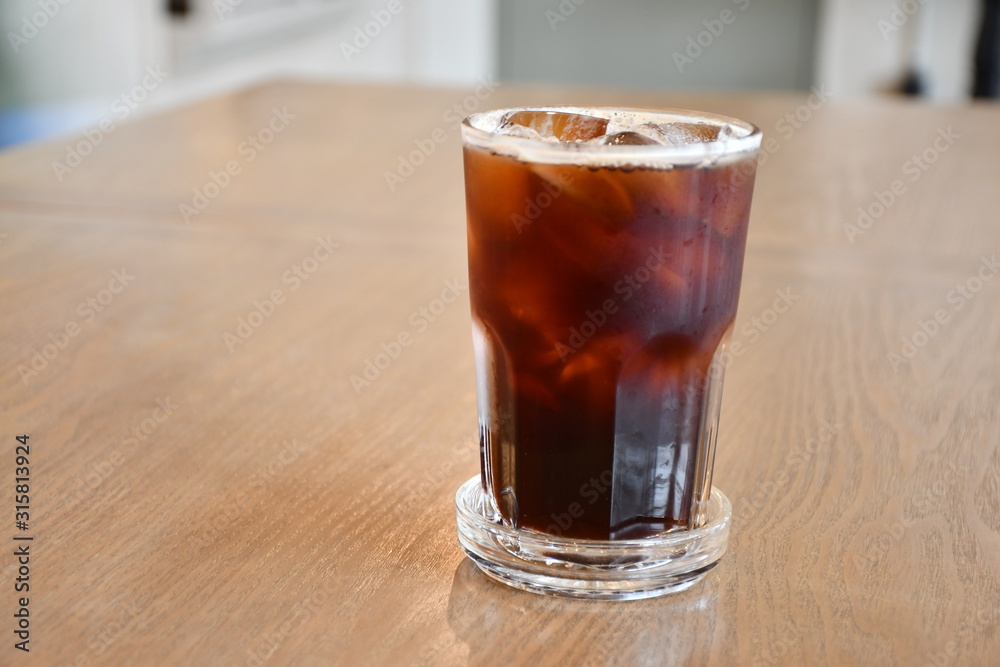 A glass of ice Americano on wooden table in cafe. A glass of ice Americano on wooden table in cafe.