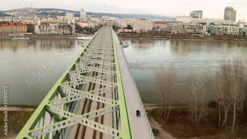 Flying asymmetrically above the Old Bridge in the city of Bratislava, Slovakia. Aerial drone video with the camera moving forward, following the bridge metal construction. photo