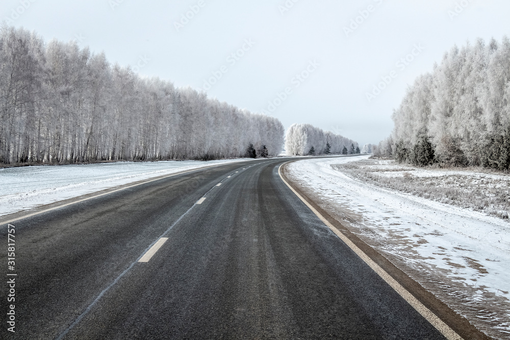 Highway among trees covered with thick hoarfrost.