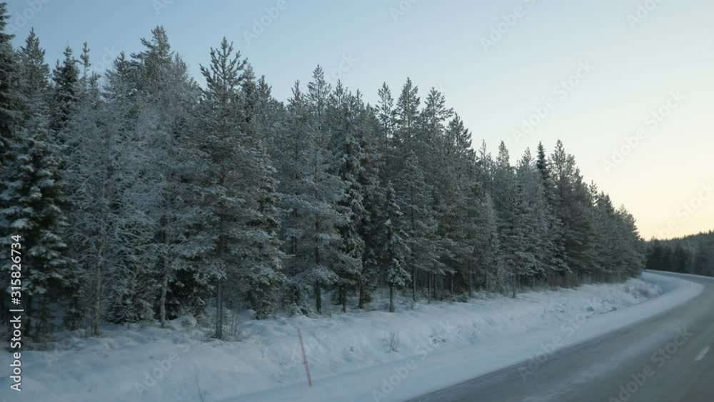 Icy highway road with lofty spruce trees around turning left in frosty Finland Icy highway road with lofty spruce trees around turning left in frosty Finland