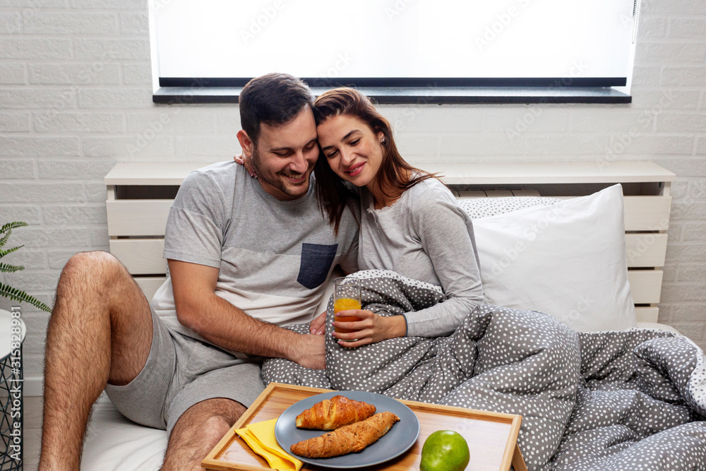 Beautiful happy couple in the morning with breakfast in bed