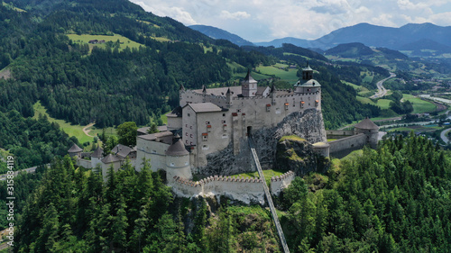 Aerial panoramic view of Hohenwerfen Castle, Austria. Medieval rock fortress in Alpine mountains with spruces. Overlooking the Werfen town in Salzach valley. Summer. © dimabucci
