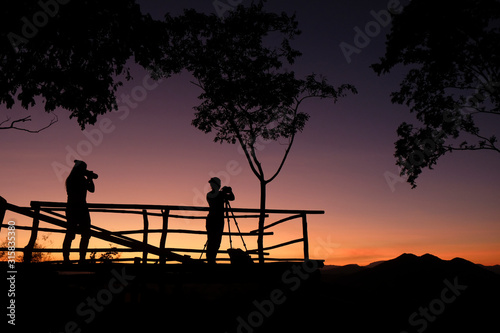photographer silhouette on the mountain taking photo shooting landscape with sunset or sunrise - photographer woman with camera