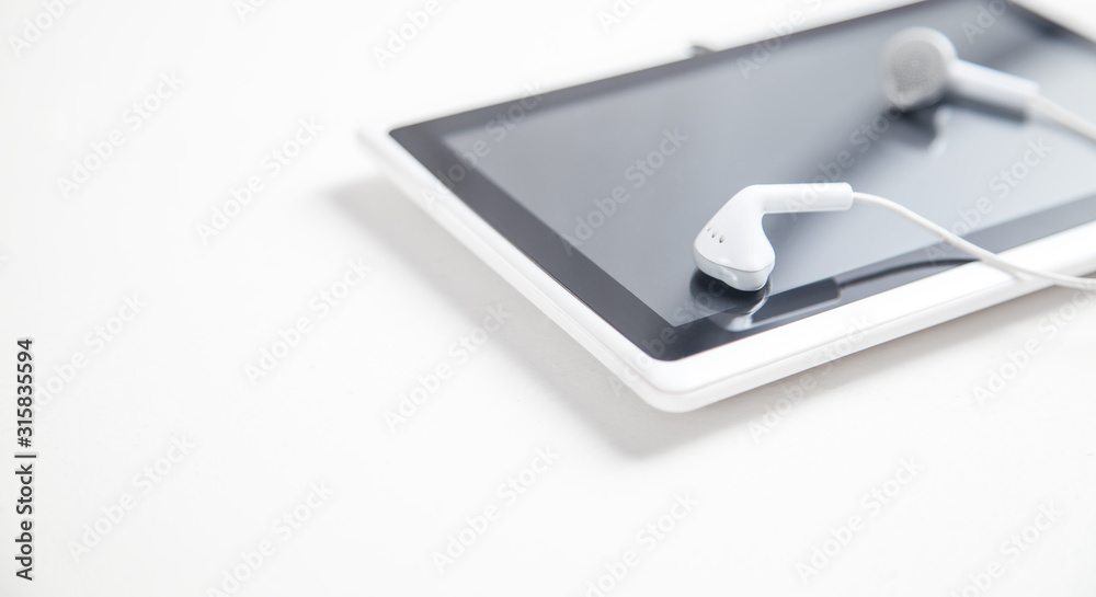 Tablet with a earphones on white desk. Tablet with a earphones on white desk.
