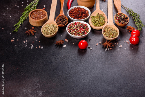A set of spices and herbs. Indian cuisine. Pepper, salt, paprika, basil and other on a dark background