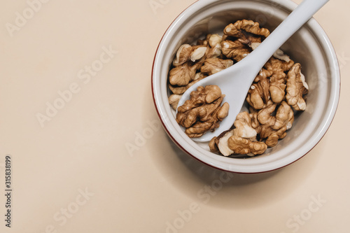 Pile of shelled walnuts in glass bowl, healthy eating concept 