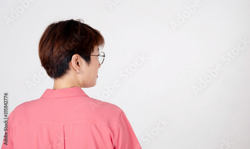 Portrait of short-haired Asian woman Wearing a pink shirt smiling side-facing On a white background