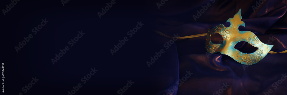 Naklejka premium Photo of elegant and delicate gold Venetian mask over purple silk background