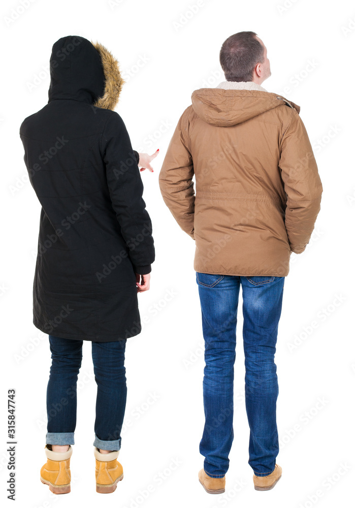 Back view of couple couple in winter jackets pointing.