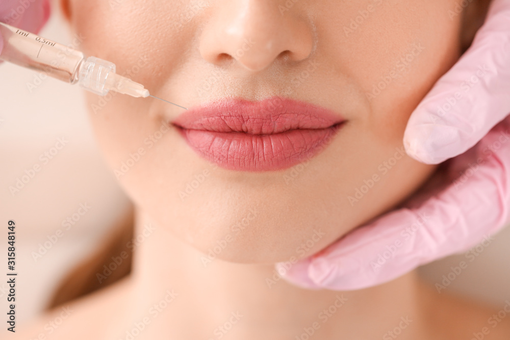 Young woman receiving filler injection in beauty salon, closeup