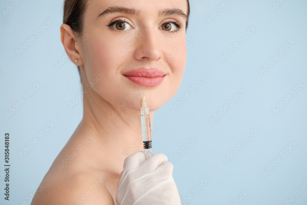 Young woman receiving filler injection against color background Young woman receiving filler injection against color background