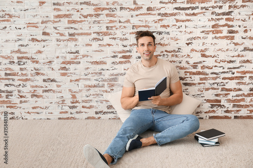Handsome young man reading ...