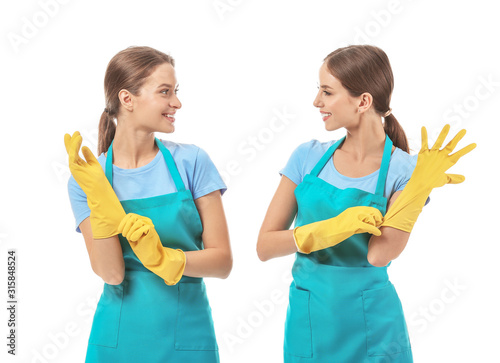 Female janitors putting on rubber gloves against white background