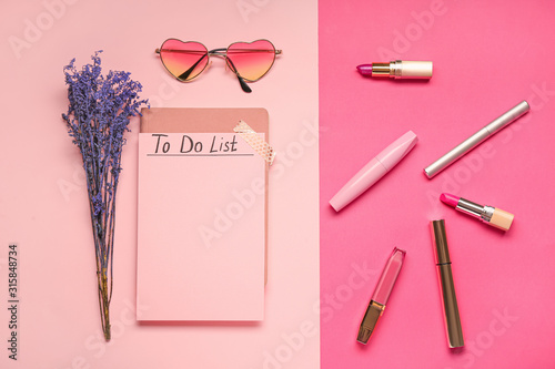 Empty to do list with makeup cosmetics and sunglasses on color background