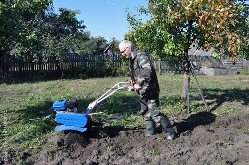 plowing the land in the garden with a cultivator. a man plows the land with the help of motor cultivator.