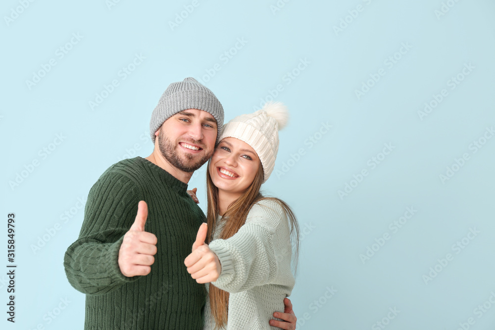 Portrait of happy couple in winter clothes showing thumb-up gesture on color background Portrait of happy couple in winter clothes showing thumb-up gesture on color background