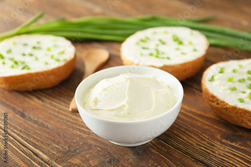Bowl with tasty cream cheese on table
