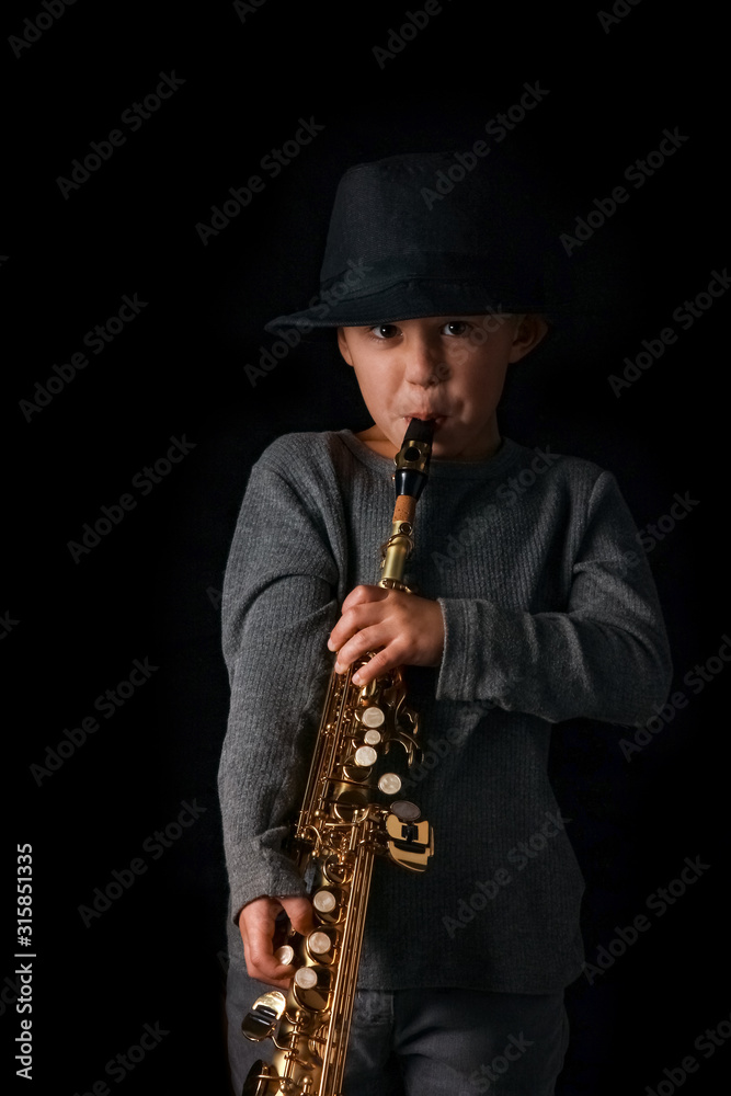Naklejka premium happy child plays saxophone in studio