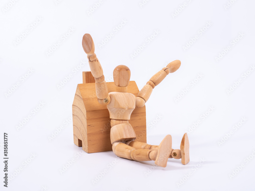 Man leaned against the model of a house isolated on white background. Concept with a wooden puppet Man leaned against the model of a house isolated on white background. Concept with a wooden puppet