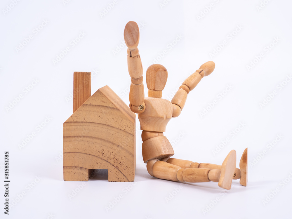 Man leaned against the model of a house isolated on white background. Concept with a wooden puppet Man leaned against the model of a house isolated on white background. Concept with a wooden puppet