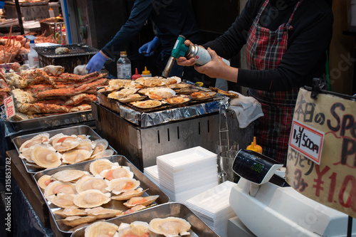 Osaka, Japan January 3, 2020: The shop is cooking the scallops in Kuromon fresh market in Japan. photo