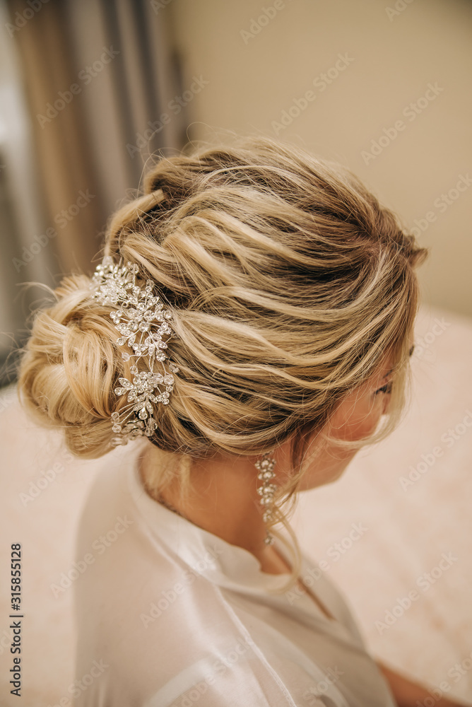 Elegant female hairstyle on blond hair. Weaving with decoration. Hairstyle bride