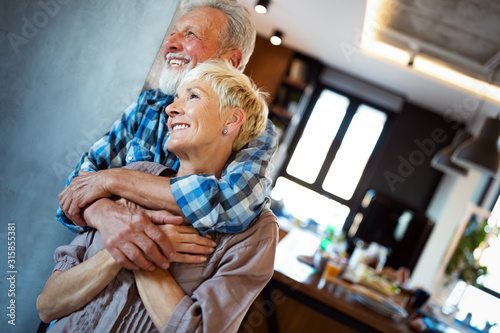 Happy smiling senior couple embracing together at home