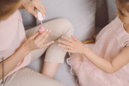 Beautiful young asian mother is painting the nail varnish to her cute little daughter.