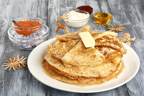 Plate with delicious thin pancakes and topping on wooden background