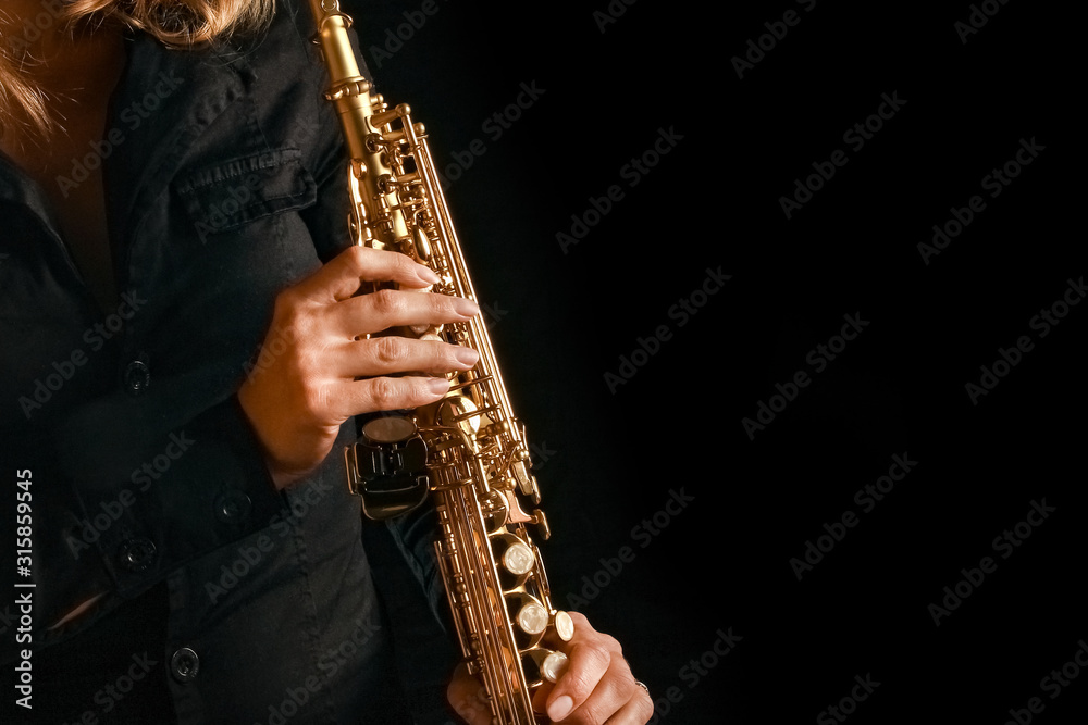 Fototapeta premium soprano saxophone in the hands of a girl on a black background