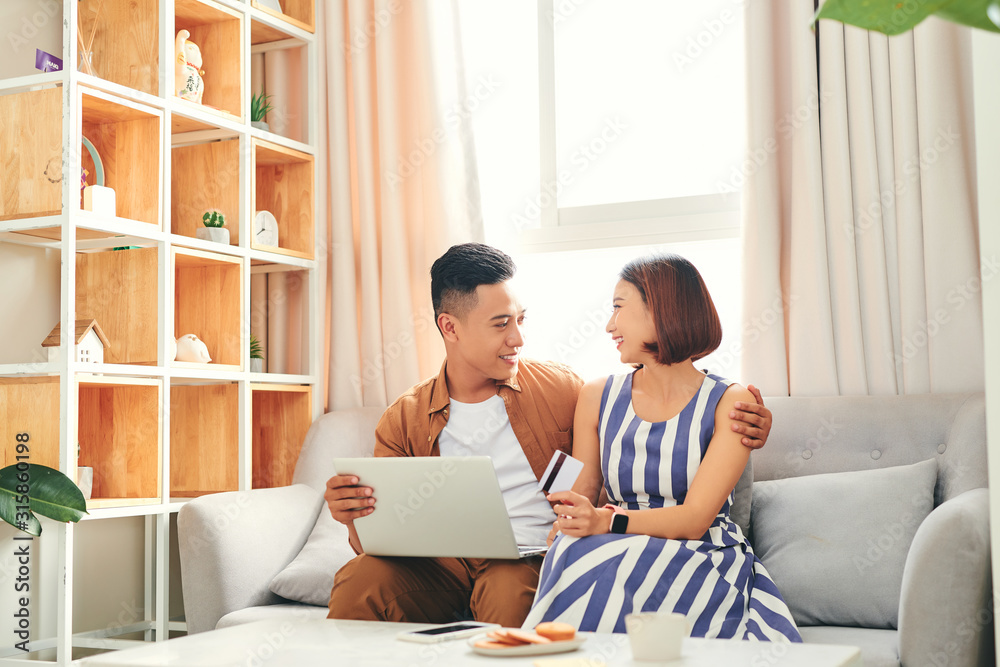 Beautiful Asian Couple Using Bank Card Online With a Laptop at home Beautiful Asian Couple Using Bank Card Online With a Laptop at home