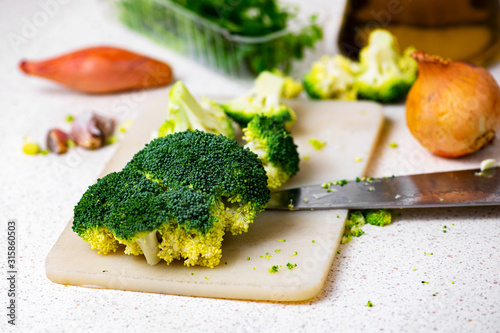 Broccoli, onion, garlic and knife on kitchen board.