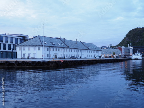 White building in european Alesund town reflected in water in Norway