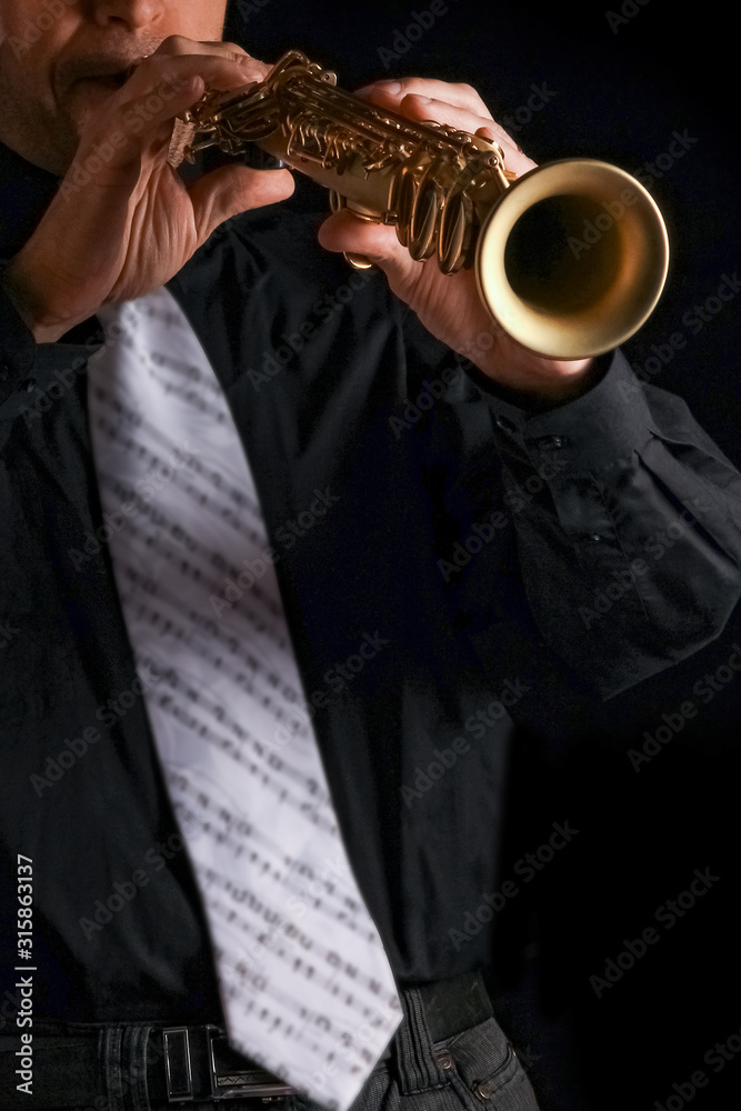 Obraz premium soprano saxophone in the hands of a guy on a black background