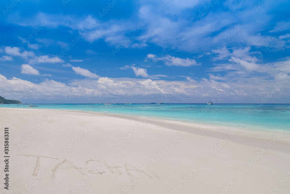 view of Tachai Text on white sand beach with blue-green sea and cloudy sky background,  Tachai island, Mu Ko Similan National Park, Phang Nga, south of Thailand.
