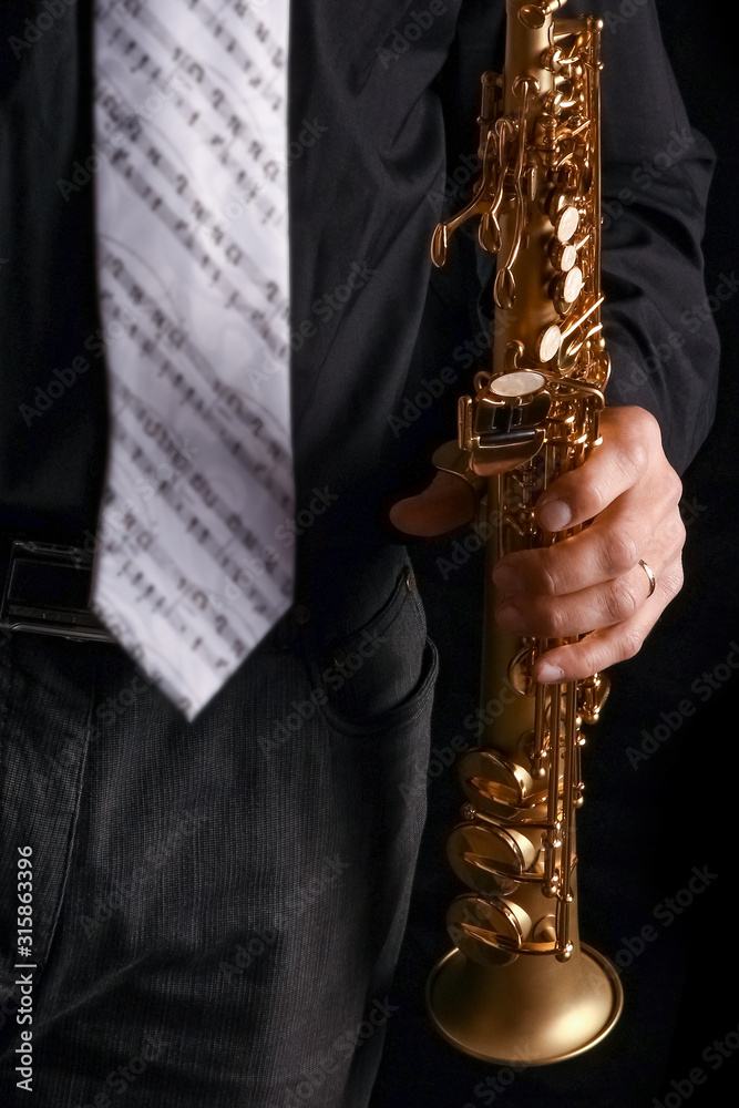 Naklejka premium soprano saxophone in the hands of a guy on a black background