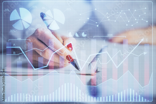 Double exposure of woman's hands making notes with forex graph hologram. Concept stock market analysis.