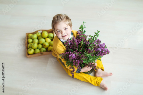 Child boy with bacon of lilac closeup and a basket of fruit.