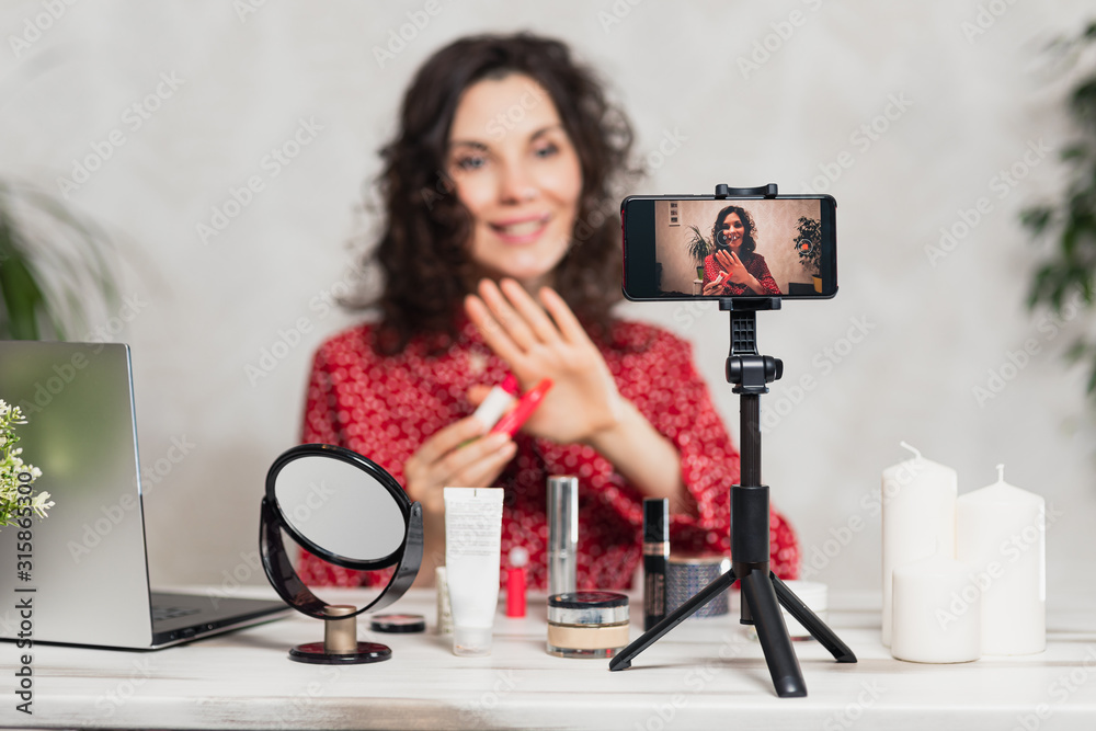 Influencer Young girl blogger talks about makeup. Woman recording video blog tells how to be beautiful. Bloger talks facial beauty treatments. Vloggre broadcasts how to use of cosmetic